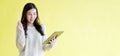 Young asian woman holding digital tablet , smiling while standing over isolated yellow background with copy space Royalty Free Stock Photo