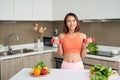 Young Asian woman holding dumbell and wearing sportive clother in kitchen