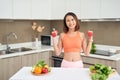 Young Asian woman holding dumbell and wearing sportive clother in kitchen