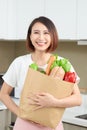 Young Asian woman holding grocery shopping bag with vegetables in the kitchen Royalty Free Stock Photo