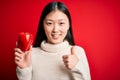 Young asian woman holding healthy and fresh red pepper over isolated background happy with big smile doing ok sign, thumb up with