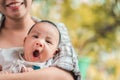 Young asian woman holding a newborn baby in her arms, baby yawning, Selective focus Royalty Free Stock Photo