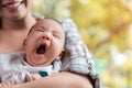 Young asian woman holding a newborn baby in her arms, baby yawning, Selective focus Royalty Free Stock Photo