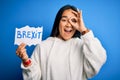 Young asian woman holding paper with brexit message over isolated blue background with happy face smiling doing ok sign with hand Royalty Free Stock Photo