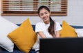 Young asian woman holding remote control and enjoy watching tv in living room at home,sitting on sofa Royalty Free Stock Photo