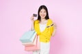Young asian woman holding shopping bags and showing credit card isolated on color background Royalty Free Stock Photo