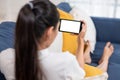 Young asian woman holding smartphone with blank white screen ,lying down cozy on sofa in living room,technology electronic gadget Royalty Free Stock Photo