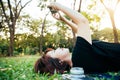 Young Asian woman laying on the green grass listening to music in the park with a chill emotion. Royalty Free Stock Photo