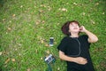 Young Asian woman laying on the green grass listening to music in the park with a chill emotion. Royalty Free Stock Photo