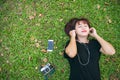 Young Asian woman laying on the green grass listening to music in the park with a chill emotion. Royalty Free Stock Photo