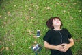 Young Asian woman laying on the green grass listening to music in the park with a chill emotion. Royalty Free Stock Photo