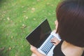 Young asian woman legs on the green grass with open laptop. Girl hands on keyboard. Distance learning concept. Royalty Free Stock Photo