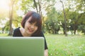 Young asian woman legs on the green grass with open laptop. Girl hands on keyboard. Distance learning concept. Royalty Free Stock Photo