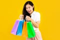 Young asian woman long hair style in black and white costume carrying the colorful paper shopping bags on yellow background Royalty Free Stock Photo