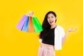 Young asian woman long hair style in black and white costume carrying the colorful paper shopping bags on yellow background Royalty Free Stock Photo