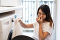 Young Asian woman looking at  dirty smelly clothe out of washing machine in kitchen Royalty Free Stock Photo