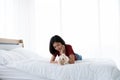 A young Asian woman lounging with a maltese dog on a white bed Royalty Free Stock Photo