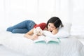 A young Asian woman lounging with a maltese dog on a white bed Royalty Free Stock Photo