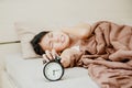 Young Asian woman lying in bed and hates to wake up early in the morning. Sleepy girl stretching hand to ringing alarm willing Royalty Free Stock Photo