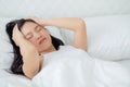 Young asian woman lying on bed pain headache in the bedroom at home, unhappy female exhaustion and sick headache. Royalty Free Stock Photo