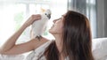 Young Asian woman lying on bed woke up and greeted by a cockatoo parrot in the morning