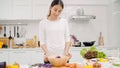 Young Asian woman making salad healthy food in the kitchen, beautiful female in casual use organic vegetables lots of nutrition Royalty Free Stock Photo