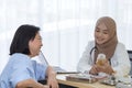 Young asian woman muslim doctor holding the bottle of pills and explaining to elderly patient in the hospital office Royalty Free Stock Photo