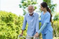 Young Asian woman nurse care giver helping senior old man with mobility walker in garden at home. Senior daycare center, Nurse Royalty Free Stock Photo