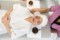 Young asian woman with nutrient facial dressed in bathrobe, getting facial care by beautician at spa salon, Top View. Face peeling Royalty Free Stock Photo