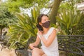 Young Asian woman outdoors during covid19 - lifestyle portrait of beautiful and happy Chinese girl in face mask smiling relaxed Royalty Free Stock Photo