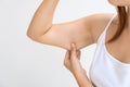 Young Asian woman pinching loose skin or flab on her upper arm on white background. Health care and medical concept