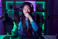 Young asian woman playing video games with smartphone smelling something stinky and disgusting, intolerable smell, holding breath Royalty Free Stock Photo