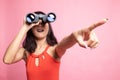 Young Asian woman point and look with binoculars