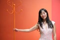 Young asian woman pose with a red orange monochrome coat rack. Studio shot.