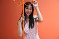 Young asian woman pose with a red orange monochrome coat rack. Studio shot.