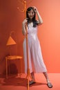 Young asian woman pose with a red orange monochrome coat rack. Studio shot.