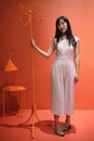 Young asian woman pose with a red orange monochrome coat rack. Studio shot