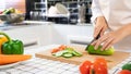 Young Asian woman is preparing healthy food vegetable salad by Cutting cucumber for ingredients on cutting board on light kitchen Royalty Free Stock Photo