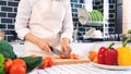 Young Asian woman is preparing healthy food vegetable salad by Cutting tomato for ingredients on cutting board on light kitchen, Royalty Free Stock Photo