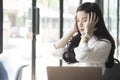 young asian woman put hand on head feeling tired at office. businesswoman frustrate and stress from hard work while sitting Royalty Free Stock Photo