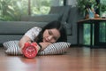 Young asian woman reaching over to turning off alarm clock while lying on the floor in living room at home Royalty Free Stock Photo