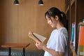 Young asian woman reading book in library. Royalty Free Stock Photo