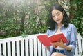 Young Asian woman reading a book relaxing in chair at garden on Royalty Free Stock Photo