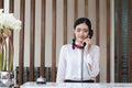 Young Asian woman receptionist behind the hotel counter talking on the phone, Female receptionist working in the hotel Royalty Free Stock Photo