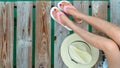 Young Asian woman with red pedicure wearing pink and white sandals sit on wooden bridge and put hat beside legs on holiday. Summer Royalty Free Stock Photo