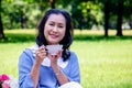 Young Asian woman relax time in park.In the morning she is sipping tea , Royalty Free Stock Photo