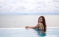 A young woman relaxing in infinity swimming pool with a beautiful sea view Royalty Free Stock Photo