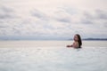 A young woman relaxing in infinity swimming pool looking at a beautiful sea view Royalty Free Stock Photo