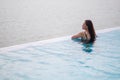 A young woman relaxing in infinity swimming pool looking at a beautiful sea view Royalty Free Stock Photo