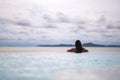 A young woman relaxing in infinity swimming pool looking at a beautiful sea view Royalty Free Stock Photo